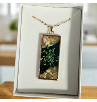 Pendentif en résine noire et dorée , fleur séchée naturelle verte .