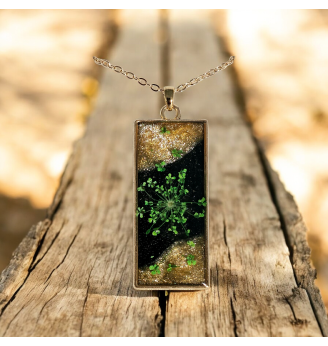 Pendentif en résine noire et dorée , fleur séchée naturelle verte .