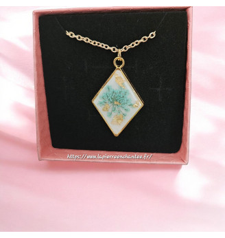 Pendentif en résine, losange doré et fleur naturelle turquoise – Fond blanc .