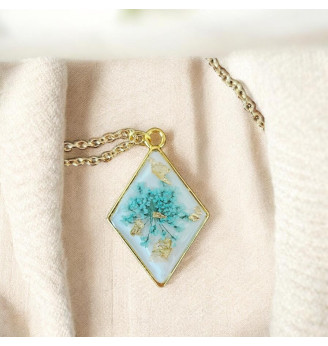Pendentif en résine, losange doré et fleur naturelle turquoise – Fond blanc .