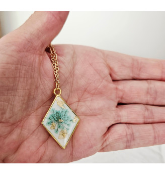 Pendentif en résine, losange doré et fleur naturelle turquoise – Fond blanc .