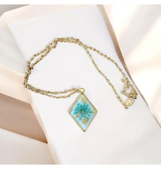 Pendentif en résine, losange doré et fleur naturelle turquoise – Fond blanc .