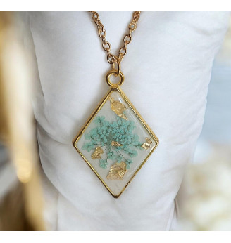 Pendentif en résine, losange doré et fleur naturelle turquoise – Fond blanc .